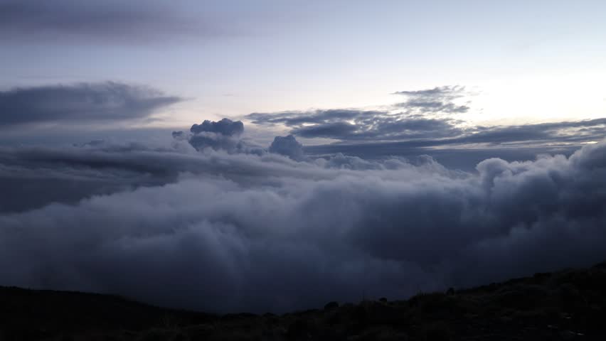 View from the summit of Mount Kilimanjaro in Tanzania with vast clouds below, glaciers, and endless plains stretching to the horizon. High-altitude panorama scene showing snow-covered summit area, crater rim views, dramatic elevation perspective, sunrise or sunset light over Africa, extreme mountain environment, and breathtaking landscape from the highest peak on the continent