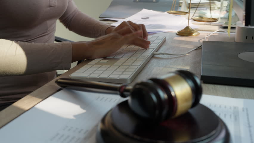 Lawyer typing on keyboard with judge gavel in foreground at office desk, representing legal work, law firm operations, justice system, and modern professional legal workflow concept.