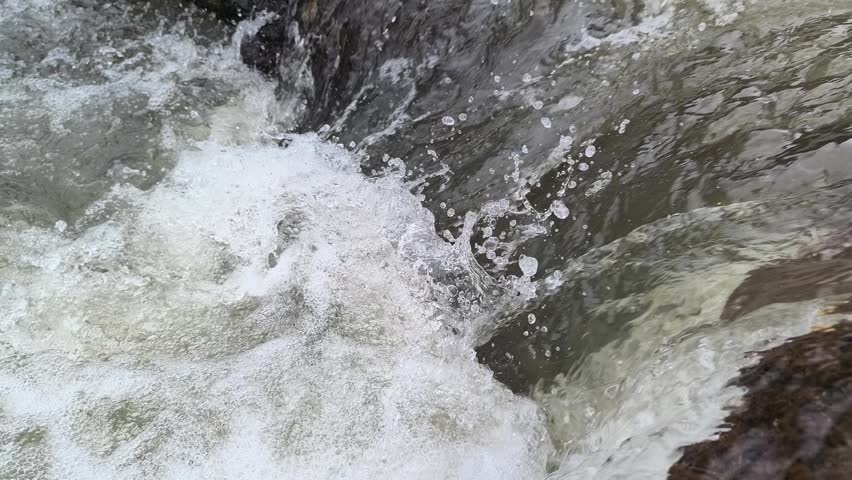 Flowing river rapids with fast-moving water over rocks, creating dynamic splashes and natural energy, capturing the power and motion of a wild stream
