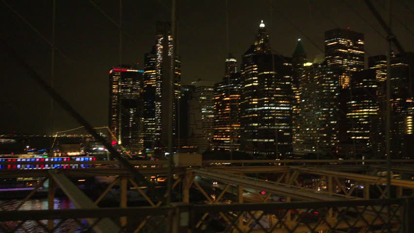 Lower Manhattan skyline framed by bridge cables at night New York