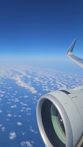 Aerial View of Airplane Wing Over Clouds in Clear Blue Sky