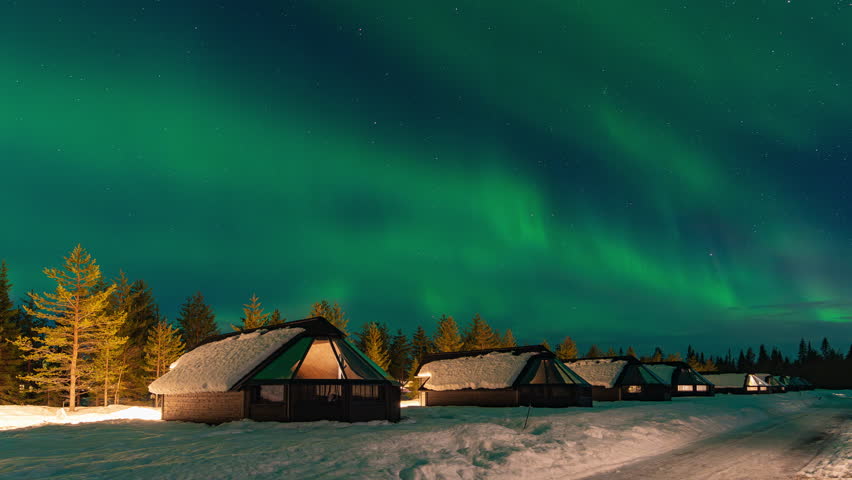 Time lapse : Snow-covered village, Lapland, Northern Finland, rural houses with glass roof, snow covered. Aurora borealis beyond the Arctic Circle. Levi, Finland