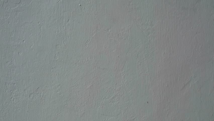 Hand sticking a white square paper note with the word Revision on a textured wall.
