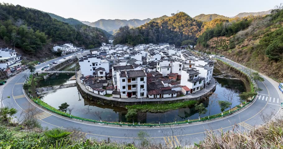 Time-lapse of the traditional village encircled by river with light trails and road at twilight, Huizhou-style settlement in Jujing Village, Wuyuan County, Jiangxi Province, China.