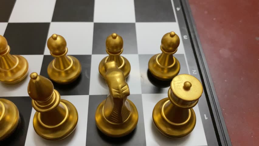 Golden chess pieces arranged on a chessboard ready to move - close up shot.