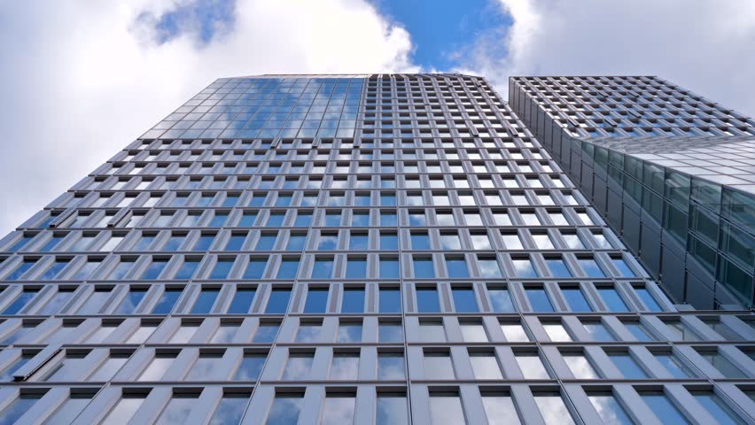 Modern glass building with blue sky and white clouds reflection on windows time lapse motion.
