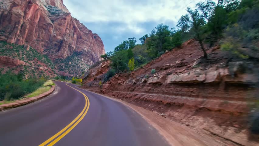 Footage captures a first-person perspective of driving along the iconic Zion-Mount Carmel Highway (Route 9) through the stunning landscapes of Zion National Park in Utah, USA.