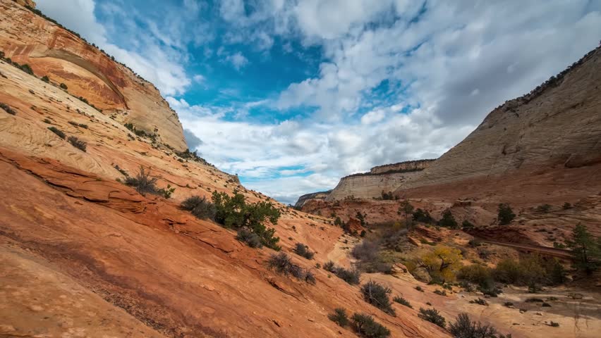 wide-angle footage of Zion National Park in Utah, USA, featuring towering red sandstone cliffs, rugged desert landscape, and a dramatic sky with clouds.