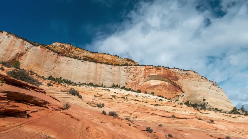A view of a blind arch (an arch still attached to the rock face) within the multi-colored, layered sandstone cliffs of Zion National Park, Utah.