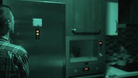 Man looking into open refrigerator at night in dark kitchen. Concept of midnight snack, hunger, unhealthy eating habits, or choosing food in a dark kitchen at night - Powered by Shutterstock - Get 15% off with code: PIKWIZARD15