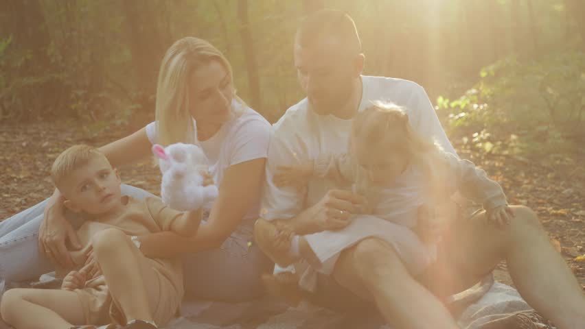 Family enjoying peaceful moments together, basking in warm sunlight filtering through forest trees, sharing genuine connection and happiness