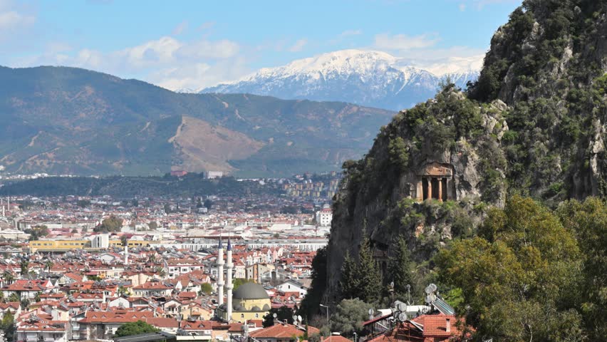 Panoramic view of the city of Fethiye, Turkey with the ancient Lycian tomb of Amyntas carved into the rock and snowy Taurus mountains