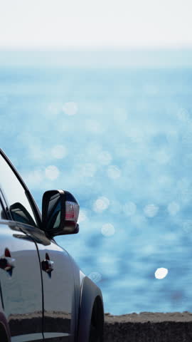 Vertical Shot of Car Parked in Scenic Parking Lot Overlooking Shimmering Ocean Below