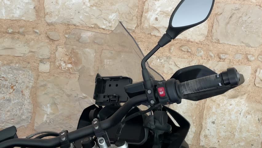 Motorcycle handlebar and mirror detail against vintage stone wall background video