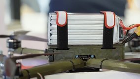Close-up of a multirotor drone with a high-capacity lithium polymer battery pack secured with straps on the frame, showing propeller hubs, power leads, and construction details - Powered by Shutterstock - Get 15% off with code: PIKWIZARD15