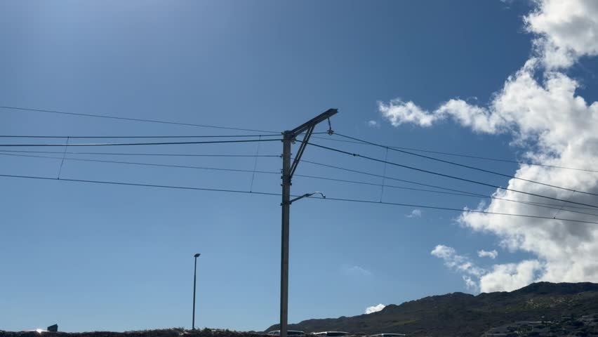 A train track pylon and overhead wire.