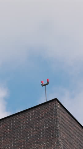 Sharp corner of modern dark brick building against blue sky with clouds. Vertical