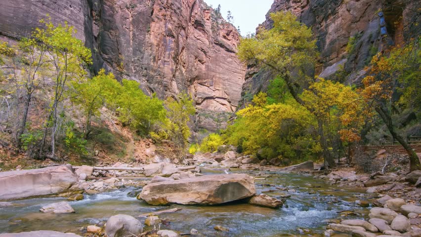 Footage of the North Fork of the Virgin River flowing through the stunning red rock canyon walls along the popular Riverside Walk trail in Zion National Park, Utah, USA.