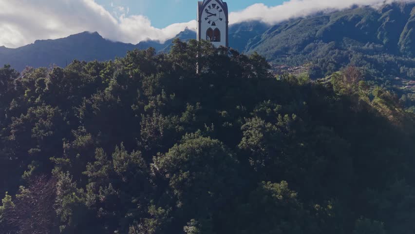 Aerial view of Nossa Senhora de Fátima chapel with terraced hills and São Vicente village in the background, surrounded by lush mountains on Madeira island.