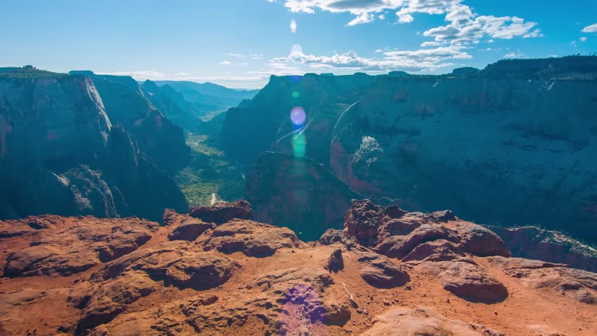 panoramic view of the iconic Zion Canyon from the top of Observation Point, accessed via the East Mesa Trail in Zion National Park, Utah, USA. The footage captures the vast, dramatic landscape of towe