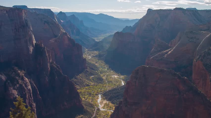 An expansive, high-angle view of the dramatic Zion Canyon from the Observation Point overlook, accessed via the East Mesa Trail in Zion National Park, Utah. The footage captures the early morning ligh