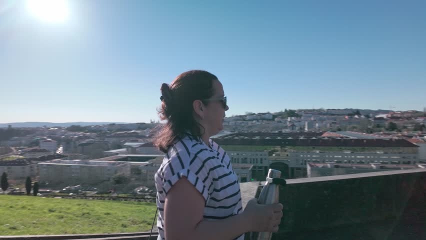 Mother and daughter excercises together while contemplating the city of Santiago de Compostela, connecting with nature and fostering their well being in a sunny setting