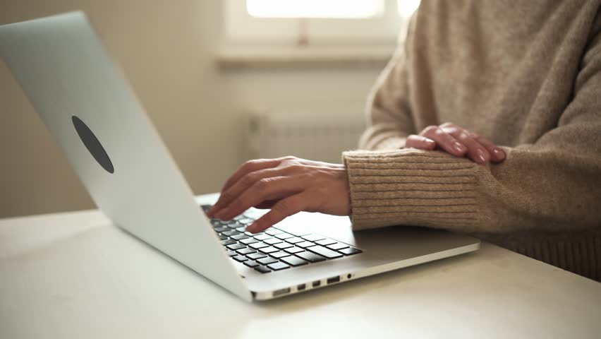 Female Hands Typing Text On A Laptop Keyboard On A Table In The Living Room