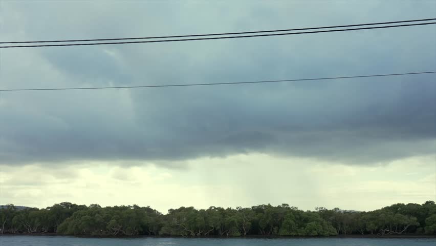 Dark storm clouds over waterway with mangrove shoreline, Woy Woy, New South Wales, Australia.