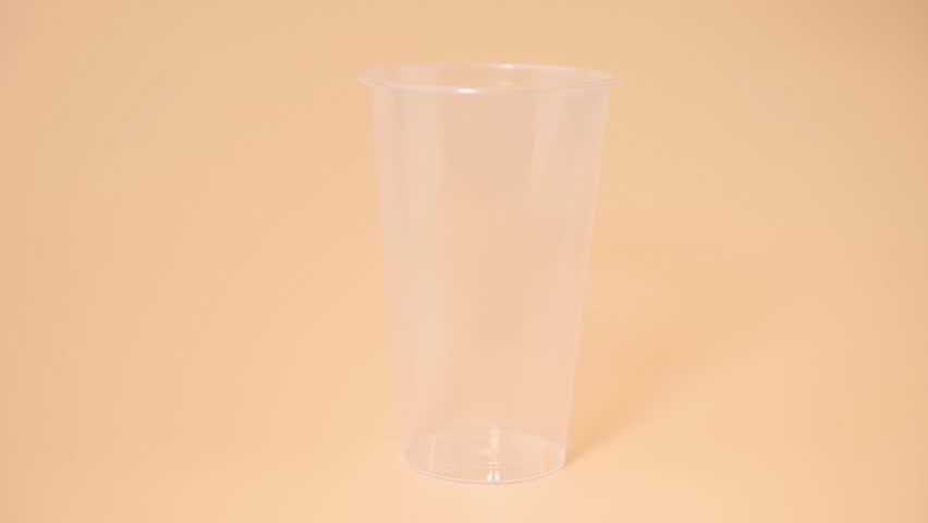 Fresh Red Yangmei Bayberry Juice Pouring into Transparent Plastic Cup on Peach Background for Food Advertising