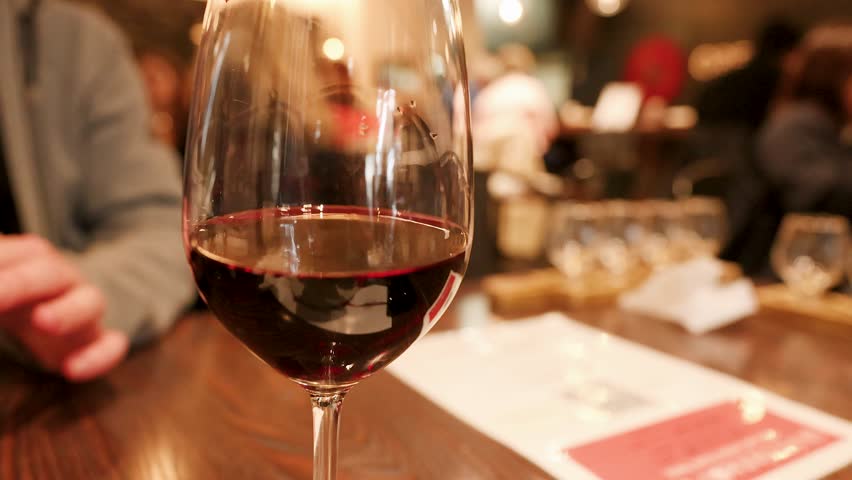 Close-up of red wine in a glass on a wooden table with bokeh background lighting