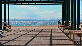 Sunlight creating intriguing shadow patterns in an outdoor pergola by the sea with person walking. - Powered by Shutterstock - Get 15% off with code: PIKWIZARD15