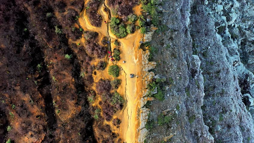 Aerial Drone Top View Looking Down at Vibrant Orange Sulfur Path Cutting Through Dark Burnt Soil. Abstract White Grey Rocky Terrain Resembling Mars Surface or Alien Planet Geology Texture Landscape 4k
