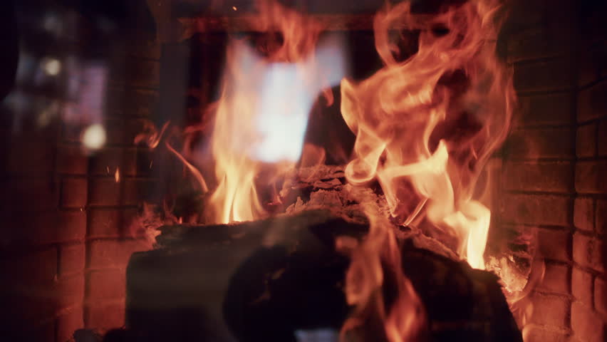 Burning firewood inside a fireplace with glowing embers and warm flames