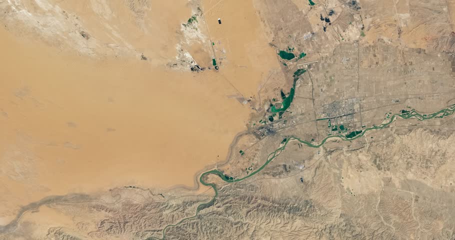 Aerial view on small town in dry desert area among sands. Camera is zooming out, rotating counterclockwise. Animation based on image by NASA
