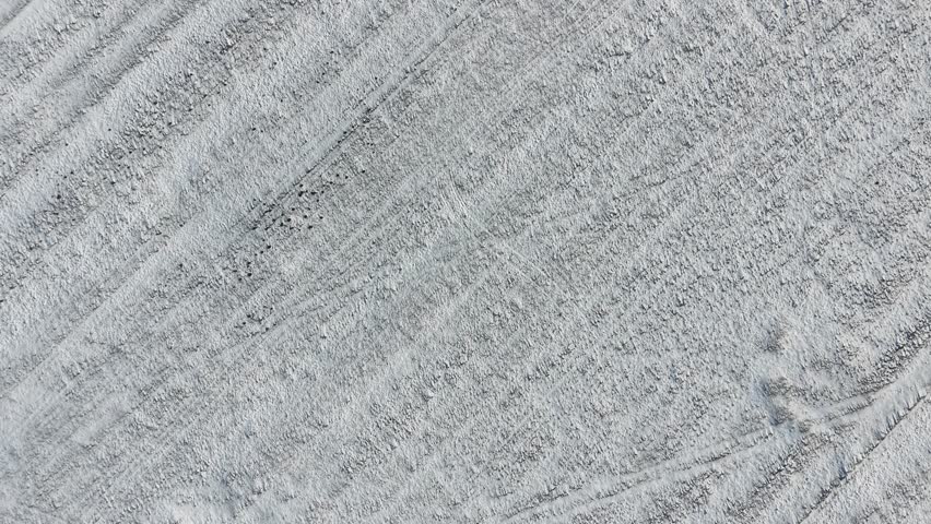 Snowy farm field showing geometric tractor track patterns