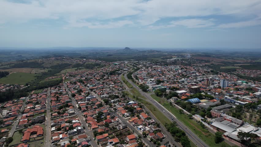 Wide cinematic aerial panorama of a coastal city in Brazil under a cloudy sky.