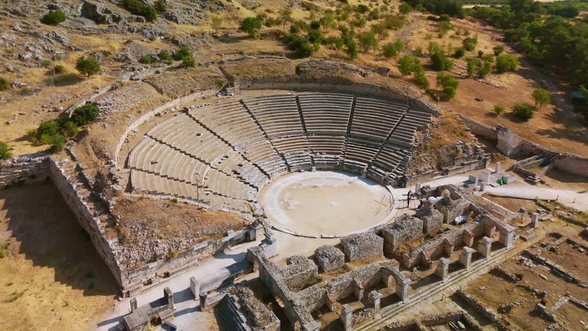 Aerial view of the UNESCO World Heritage site of Philippi, Greece. The ancient theater, Roman forum ruins, and the archaeological museum are nestled against the backdrop of the Marble mountains.