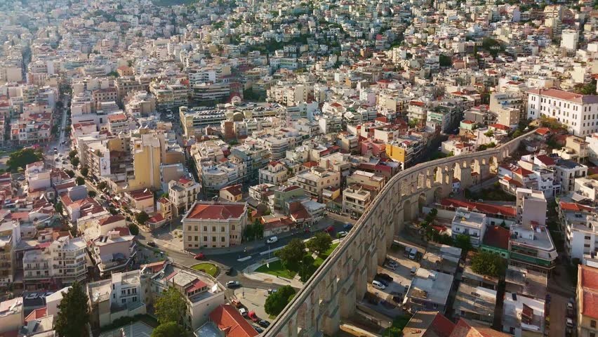 Aerial perspective of the historic old town of Kavala, Greece, dominated by the medieval fortress on the hill. Below, traditional houses, the Imaret complex, and the Ottoman-era Kamares aqueduct