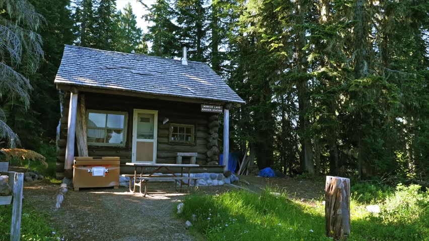 Footage of the historic Mowich Lake Patrol Cabin, a rustic log cabin ranger station built in 1922, nestled in a lush forest environment within the Mowich Lake area of Mount Rainier National Park, Wash