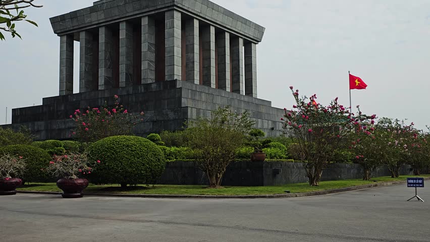 Ho chi minh mausoleum landmark in hanoi vietnam with national flag waving on cloudy day