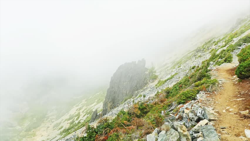 Footage capturing the steep, rocky terrain and a winding dirt trail of the Mount Fremont Lookout Trail in Mount Rainier National Park, Washington. The path ascends a high-alpine ridgeline towards