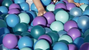 Child's hand playing in a colorful blue and purple plastic ball pit - Powered by Shutterstock - Get 15% off with code: PIKWIZARD15