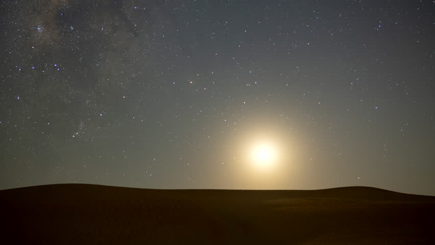 Stunning 4k timelapse of the moonset and Milky Way galaxy motion over the desert sand dune.  Moon lid the sand dunes.