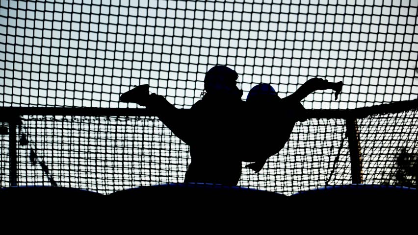 Athletic silhouette jumping high on a trampoline net, enjoying leisure and activity