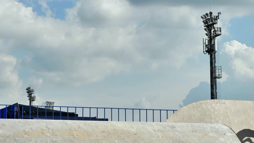 Young boy riding a kick scooter, jumping during a trick in a concrete skate park