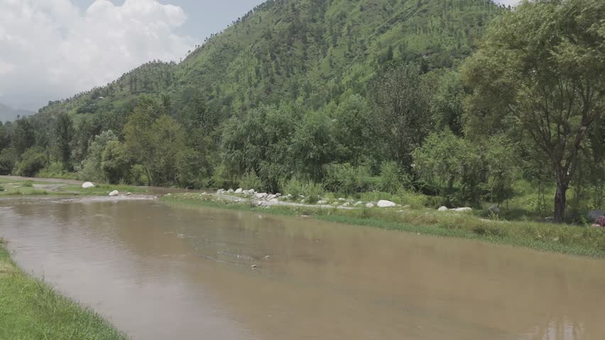 Breathtaking landscape of a wild river cutting through deep mountain valleys under a clear blue sky in Pakistan.