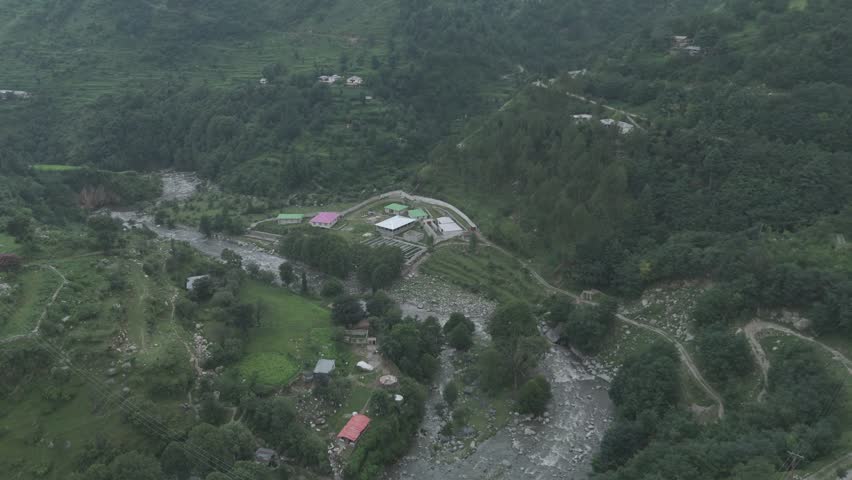 Breathtaking landscape of a wild river cutting through deep mountain valleys under a clear blue sky in Pakistan.