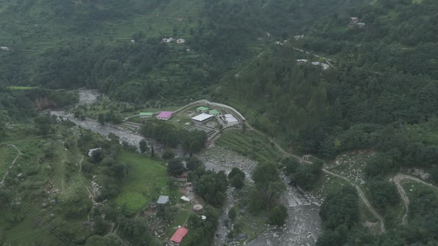 Breathtaking landscape of a wild river cutting through deep mountain valleys under a clear blue sky in Pakistan.
