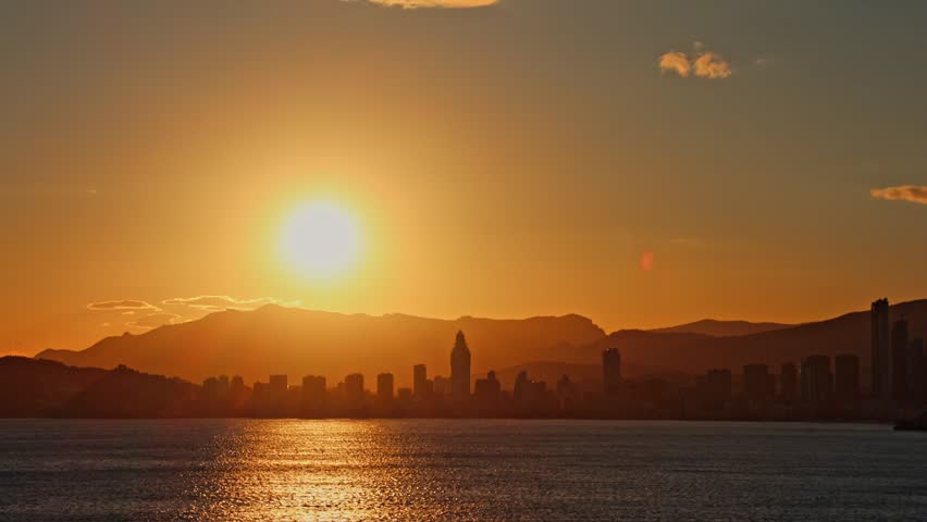 Majestic sunset over the Benidorm skyline in Spain. Skyscrapers against a vibrant sky with the Mediterranean Sea in the foreground.