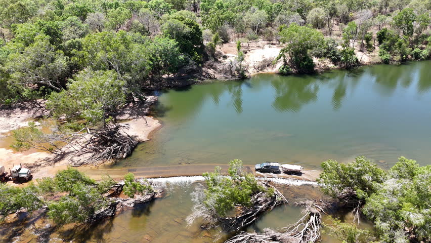 off road vehicle driving trough shallow water of a river at Kalpowar crossing at Lakefield in Queensland, popular travel destination in Australia.